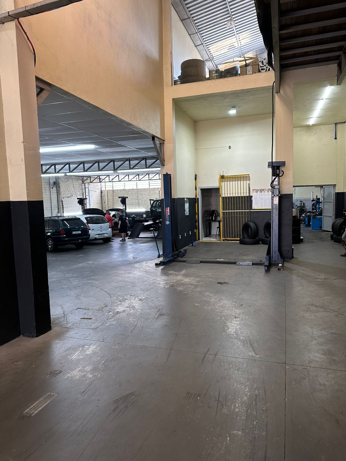 Área ampla da oficina com elevadores e veículos em manutenção